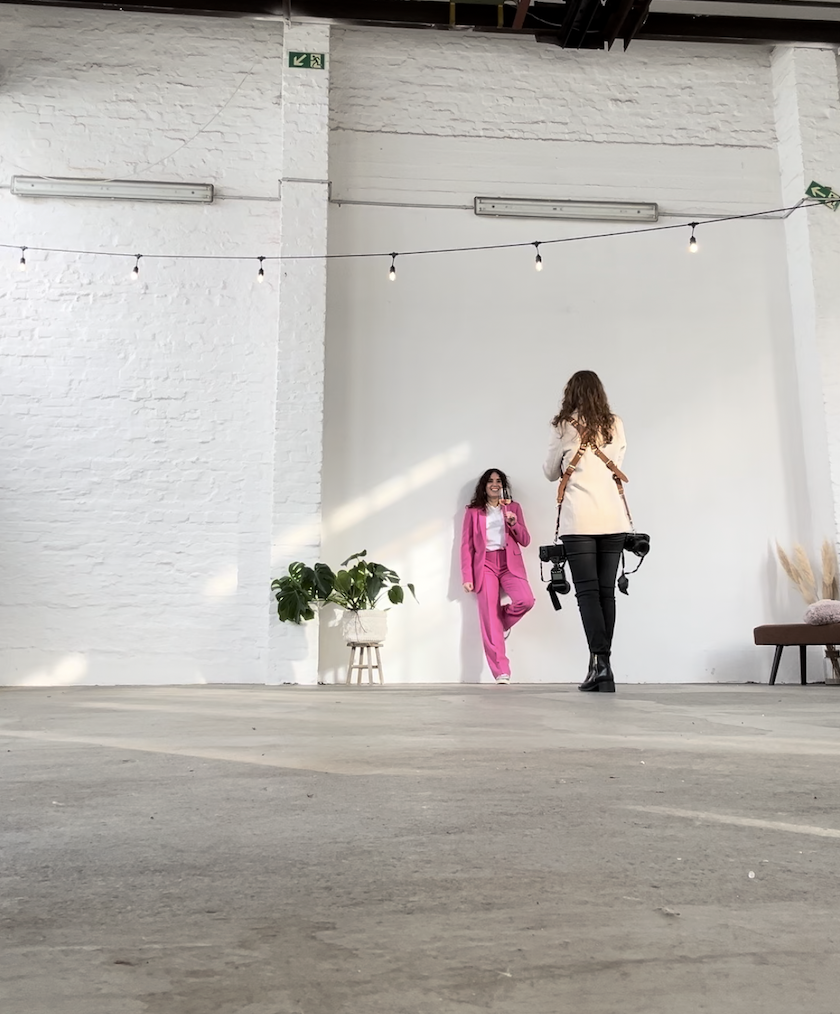 fotografin mit beigem Blazer und zwei Kameras am Gurt fotografiert selbststaendige in pinkem Hosenanzug mit Weinglas fuer Unternehmensfotos