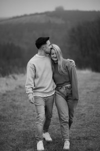 Mann und Frau gehen spazieren, waehrend Mann Frau auf die Stirn kuesst.