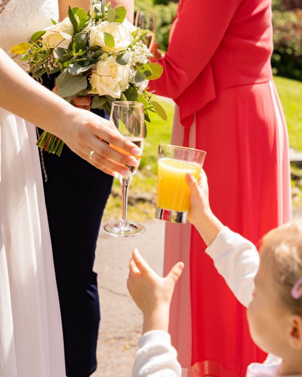 die braut prostet einem kleinen maedchen mit einem Orangensaft zu