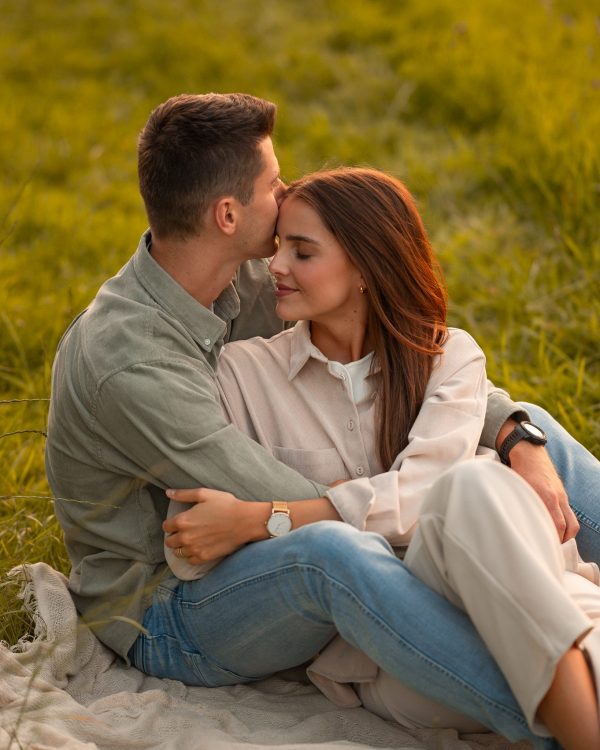 Frau sitzt im Schoss von Freund romantisch auf Picknickdecke